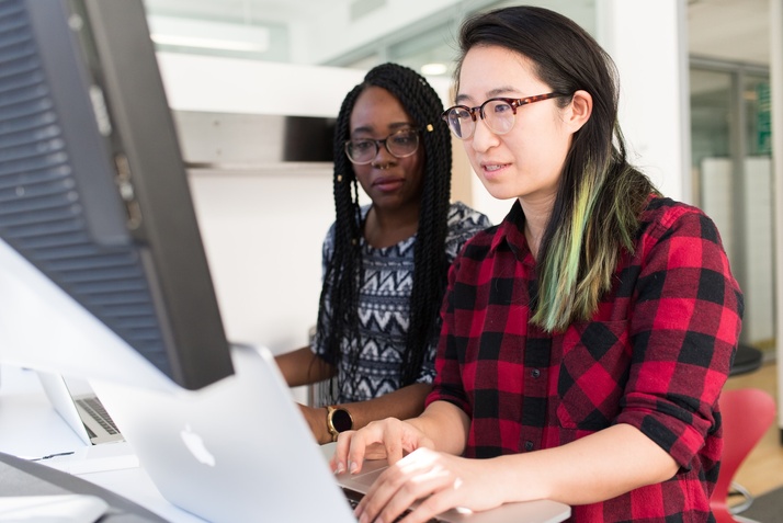 Two women using a computer to check their company metrics